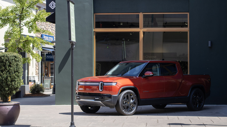 Orange Rivian R1T model positioned in front of a building